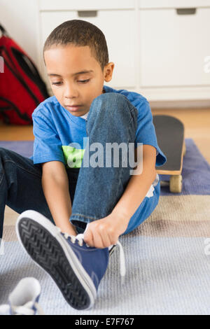 Gemischte Rassen junge seine Schnürsenkel zu binden Stockfoto