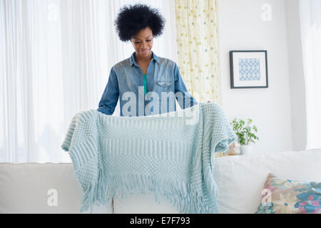 Afroamerikanische Frau Faltung Decke auf sofa Stockfoto