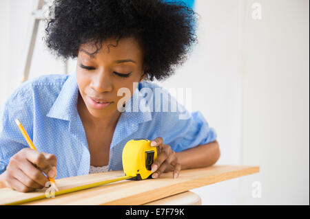 Afrikanische amerikanische Frau, die Messung von Holz Stockfoto