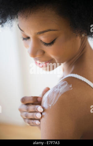 Afrikanische amerikanische Frau, die Anwendung der Feuchtigkeitscreme Stockfoto