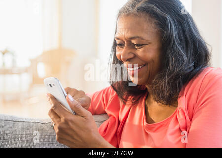 Gemischte Rassen Frau mit Handy auf sofa Stockfoto