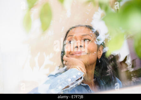 Gemischte Rassen Frau schaut aus Fenster Stockfoto