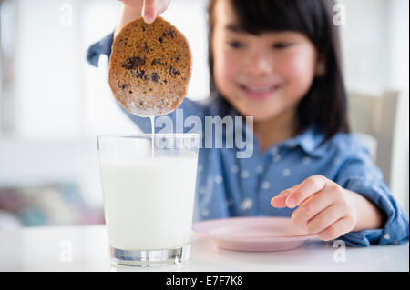 Philippinische Mädchen dunking Cookie in Milch Stockfoto