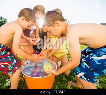 Kaukasische Kinder spielen mit Wasserballons im Hinterhof Stockfoto