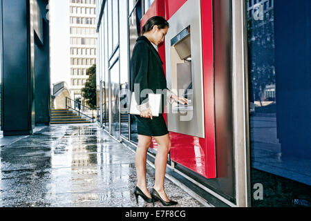 Gemischte Rassen Geschäftsfrau mit ATM in Stadt Stockfoto