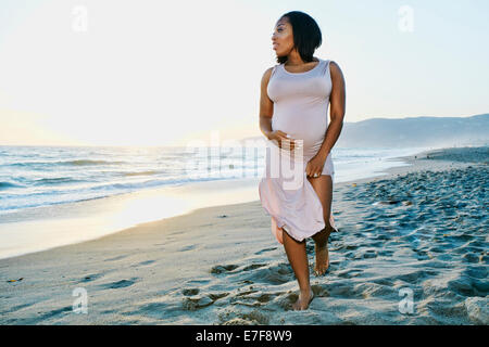 Schwangere Frau hält ihren Bauch am Strand Stockfoto
