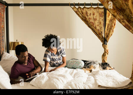 Ehepaar und Hund entspannen Sie sich auf Bett Stockfoto