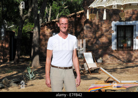 junger Mann, Stabding, sitzen im Sommergarten. Stockfoto