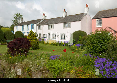 Weiß lackierter englischen Cottages mit gepflegten Gärten mit Rasenflächen und Massen von bunten Frühlingsblumen und Sträucher im Dorf Caldbeck in Cumbria. Stockfoto