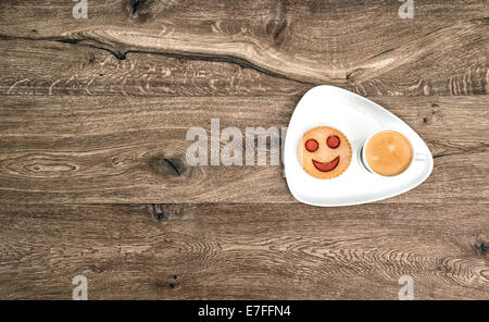 Tasse schwarzer Kaffee mit lächelte Cookie auf hölzernen Hintergrund. Stockfoto