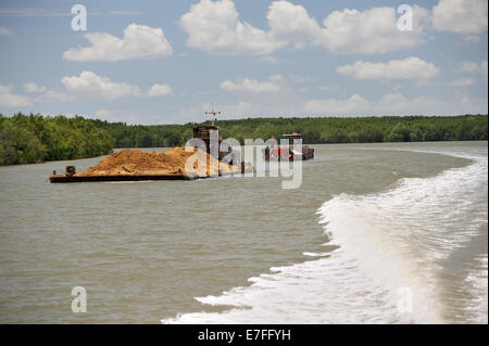 Zwei Boote auf dem Mekong River, ein schieben ein großes Schiff mit Sand gefüllt. Vietnam Stockfoto