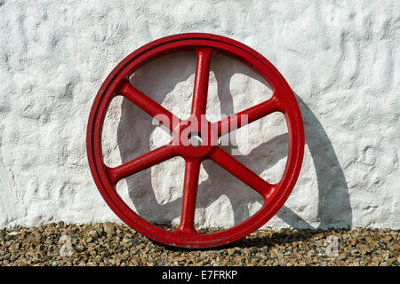 Rot lackiertem Gusseisen Rad gestützt gegen weiß gewaschen Wand des traditionellen irischen Cottage, Kilmacrennan, County Donegal, Irela Stockfoto