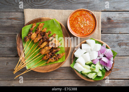 Draufsicht Malaysian Chicken Satay mit leckeren Erdnuss-Sauce, Ketupat, Zwiebeln und Gurken auf Holztisch, eines fa Stockfoto