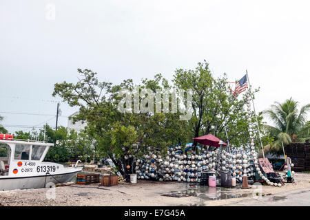 Zerfetzt und zerrissen US amerikanische Flagge snagged auf einem Ast an einem Straßenrand stehen Verkauf Styropor Schwimmer in den Florida Keys, USA. Stockfoto