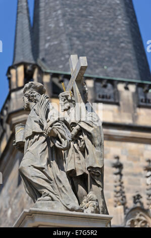 Statuen von religiösen Persönlichkeiten auf der Karlsbrücke mit dem Turm im Hintergrund, Prag, Tschechische Republik. Stockfoto