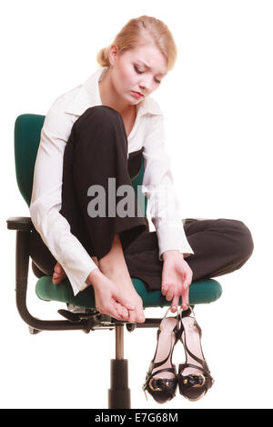 Pause von der Arbeit. Müde Geschäftsfrau mit Schmerzen in den Beinen. Junge Frau massiert ihre Füße auf Stuhl isoliert auf weiss. Stockfoto