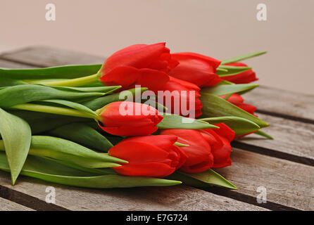 Rote Tulpen (Tulipa) liegen auf einer Holzkiste Stockfoto