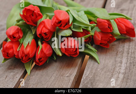 Rote Tulpen (Tulipa) liegen auf einer Holzkiste Stockfoto