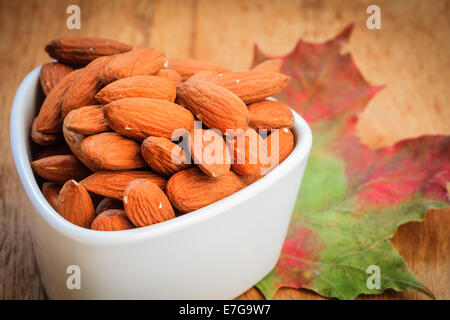 Gesundes Essen, gut für die Gesundheit des Herzens.  Mandeln in der Schüssel auf herbstliche Hintergrund weiß Stockfoto