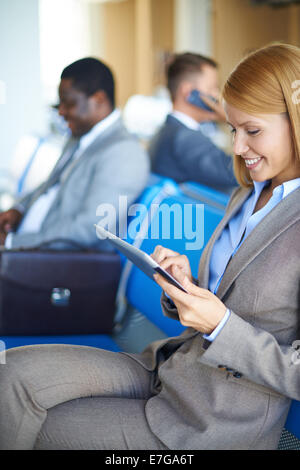 Arbeitnehmerin, die Vernetzung im Flughafen mit zwei Männer sitzen auf Hintergrund Stockfoto