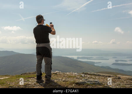 Ein Mann nimmt ein Bild mit seinem Mobiltelefon der Ansicht von Ben Lomond Stockfoto