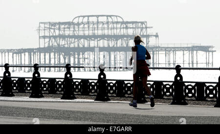 Ein Läufer übergibt der West Pier an Hove Strandpromenade am frühen Morgen Stockfoto