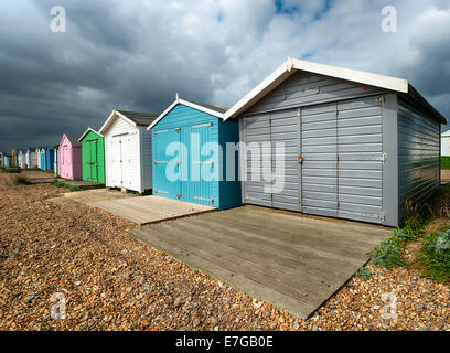 Eine Reihe von bunten Strandhäuschen unter einem dramatischen Himmel am St Leonards on Sea in Hastings, East Sussex Stockfoto