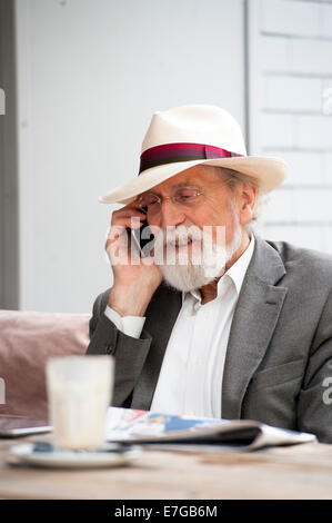 ältere Mann lächelnd und geht auf sein Handy Stockfoto