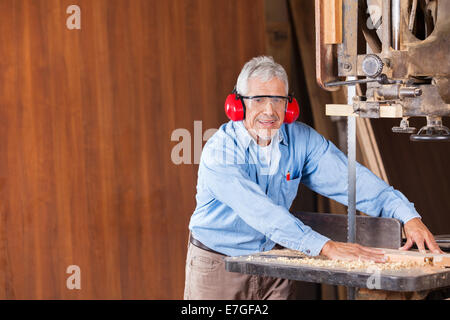 Senior Tischler Schneiden von Holz mit Bandsäge Stockfoto