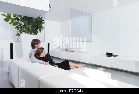 Rückansicht des jungen Paares auf Sofa vor dem Fernseher im Wohnzimmer Stockfoto