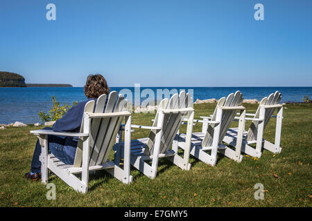 Dame in einem der vier Strandkörbe im Herbst, Blick auf den Horizont. Schuss in Door County, Wisconsin. Textfreiraum an der Spitze Stockfoto