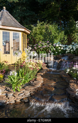 Garten - Wasser-Garten - Laube neben Wasserfall Wasserspiel Pflanzung Agapanthus "Queen Mum" Hydrang Stockfoto