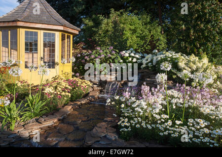 Garten - Wasser-Garten - Laube neben Wasserfall Wasserspiel Pflanzung Agapanthus "Queen Mum" Hydrang Stockfoto