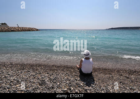 Frau sitzt auf Pebble Beach, Menton, Côte d ' Azur, Frankreich Stockfoto