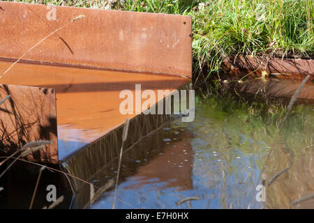 Wildtierfreundlicher Garten mit Rillenwasser aus rostem Kornstahl in einem kleinen Teich, in dem Ziergräser aus Großbritannien gepflanzt werden Stockfoto