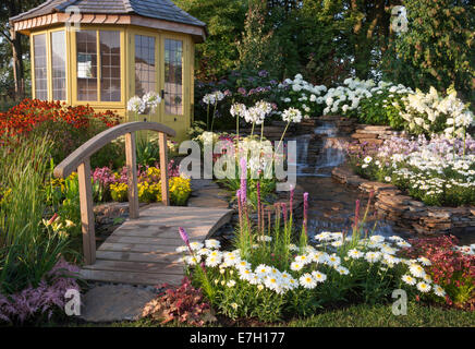 Garten - Wasser-Garten - Laube neben Wasserfall Wasserspiel mit kleinen Holzbrücke und Bepflanzung Stockfoto