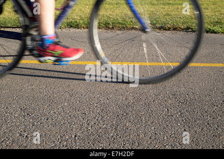 Radfahrer fahren auf der Fahrradstraße des Bow River Pathway entlang des Trans Canada Trail durch Calgary. Füße auf Pedalen, Bewegungsunschärfe Stockfoto