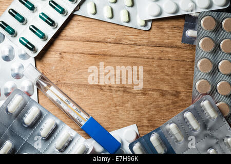 Medizinischer Hintergrund Kulisse mit Frame-Rahmen von Pillen Tabletten Drogen und Quecksilber-Thermometer auf Holztisch. Apotheke. Stockfoto