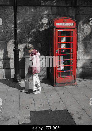 Alte Dame vorbei an roten Telefonzelle Stockfoto