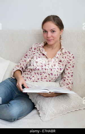 Porträt der Frau zu Hause sitzen 20-25 Jahre alt mit Buch in ihren Händen Stockfoto