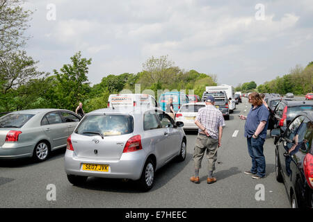 Personen, die auf der Fahrbahn vor stehenden Fahrzeugen stehen, in einem Stau auf der Autobahn M6, der durch einen Unfall verursacht wurde, der eine lange Verzögerung verursacht. England, Großbritannien Stockfoto