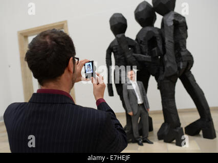 München, Deutschland. 18. Sep, 2014. Ein Mann posiert vor der Skulptur "BDM Gruoup" des Künstlers Georg Baselitz in der Ausstellung "Georg Baselitz - dazwischen, damals und heute" Haus der Kunst in München, Deutschland, 18. September 2014. Baselitz nahmen an der Pressekonferenz zur Eröffnung der Ausstellung, die seine Karriere in den vergangenen 50 Jahren dokumentiert. Es ist geöffnet vom 19. September 2014 bis 1. Februar 2015. © Dpa picture-Alliance/Alamy Live News Stockfoto