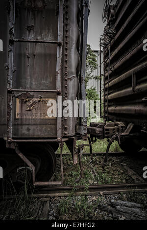 Ein dunkel und schäbig industrial-Szene mit alten rostigen Waggons gekoppelt und eine Leiter, die bis zum Dach. Stockfoto