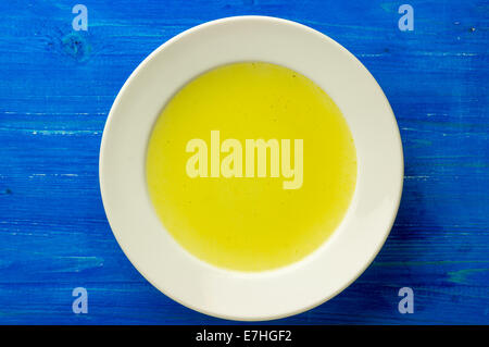 Huhn, Lager, Bouillon, Brühe, klare Suppe in einem weißen Teller auf einem blauen Brett. Ansicht von oben Stockfoto