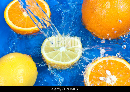 Frischen Wassertropfen auf Orangen und Zitronen und blauem Hintergrund Stockfoto