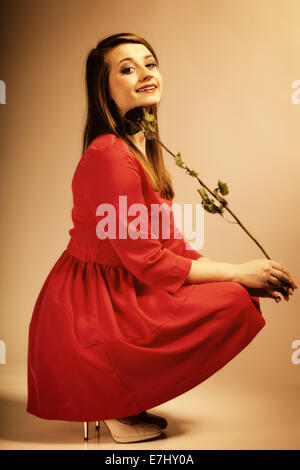 Schöne Mode Woman Teen Mädchen im roten Kleid mit trockener Rose. Foto im Stil der alten Farbe Bild. Stockfoto