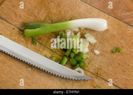 Frühlingszwiebeln und ein Messer auf ein Schneidebrett Stockfoto