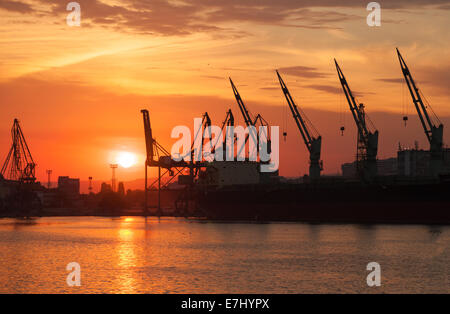 Silhouetten von Kränen und Frachtschiffe in Varna Hafen bei Sonnenuntergang Stockfoto