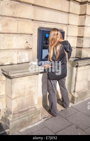 Eine Frau mit einem Barclays-Geldautomaten in Alnwick Northumberland UK Stockfoto