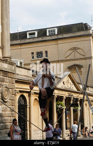 Mann zu Fuß auf Drahtseil während Geigenspiel, Busker / Street Entertainer in Bath England UK Stockfoto